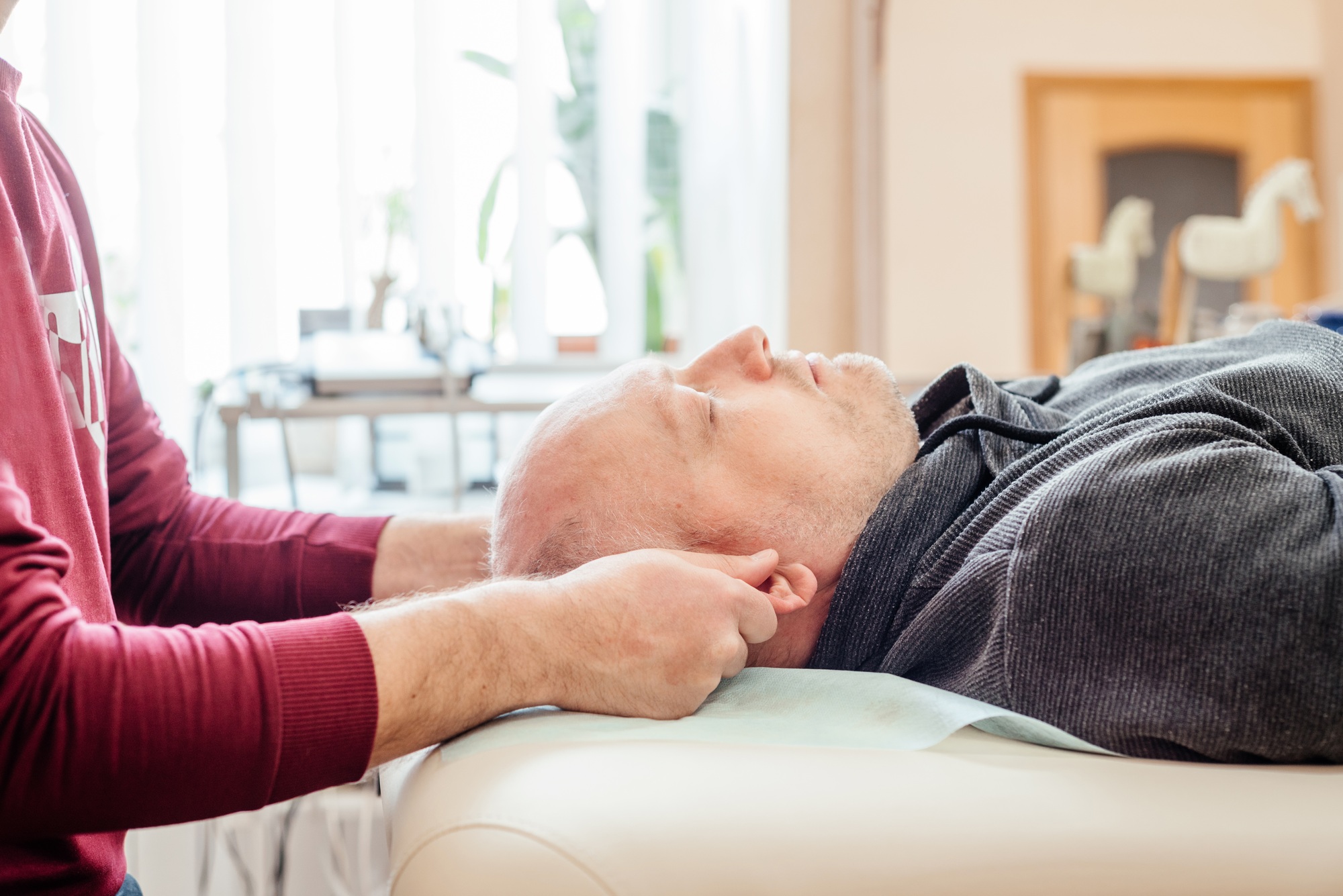 Male patient receiving cranial sacral therapy, lying on the massage table in CST osteopathy office